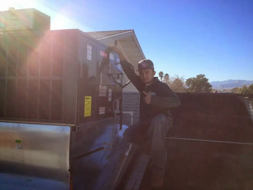 HVAC technician performing Air Duct Cleaning on a rooftop unit in Longview